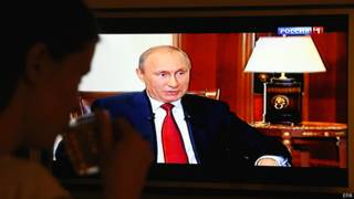 Женщина смотрит по телевидению на Владимира Путина в фильме "Крым. Возвращение домой"