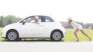 A woman pushing a car