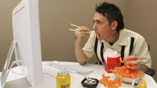 Hombre comiendo frente a computador