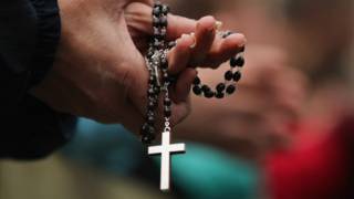 Una mujer con un rosario en las manos