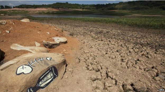 Una botella de agua y restos de pescado pintados en una roca sobre el lecho seco de un río en Sao Paulo.