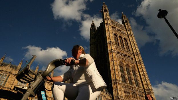 Un ciclista pasa frente a las casas del parlamento en Westminster