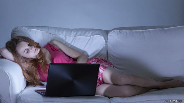 Una joven viendo su laptop en el sofá