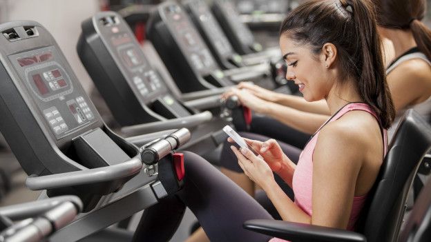 Una persona que usa el teléfono en una bicicleta estática