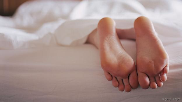 Unos pies sobresaliendo de una cama