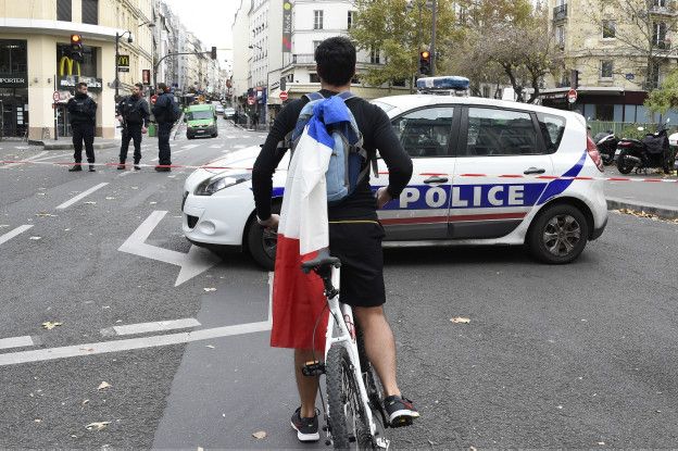 Un joven en bicileta con la bandera francesa en su mochila, frente a la zona acordonada en el distrito 10 de París, donde ocurrieron los ataques.