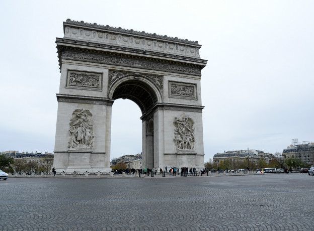 Algunas personas pasean ante un desértico Arco del Triunfo.