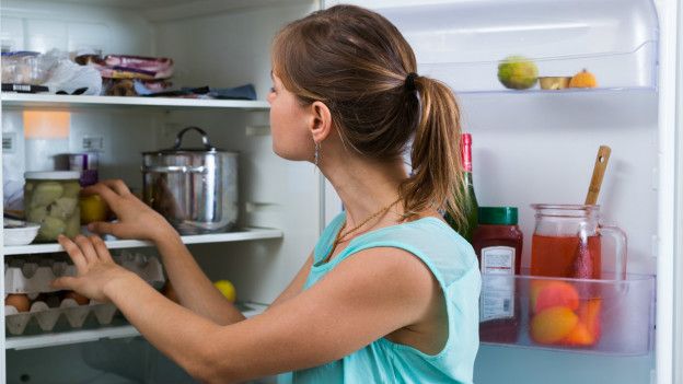 Una persona frente a la puerta abierta de un refrigerador