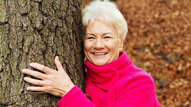 Пожилая женщина обнимает дерево