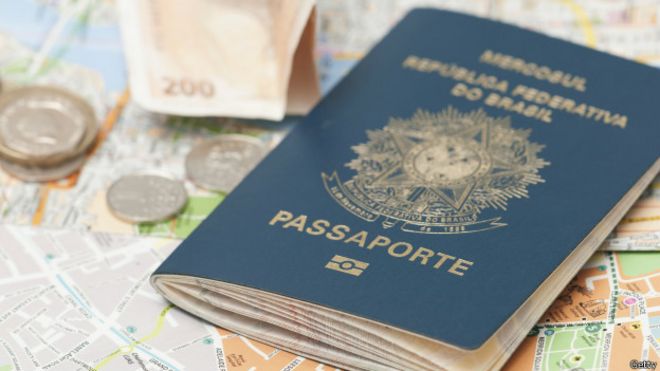 Un pasaporte brasileño descansa junto a monedas y un mapa.