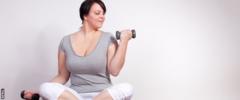 femme assise sur un tapis d'exercice tenant des poids à la main