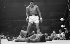 Sonny Liston looks up at a taunting Muhammad Ali