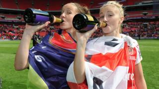 Leah Williamson drinks from a bottle with Casey Stoney