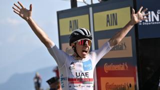Tadej Pogacar puts his arms up in celebration after winning stage 15 of the Tour de France