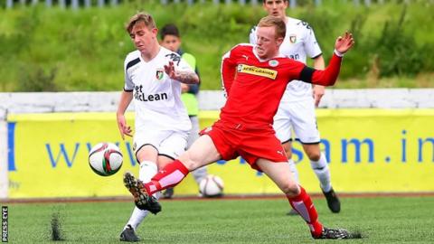Glentoran's Jonathan Smith is tackled by Cliftonville captain George McMullan