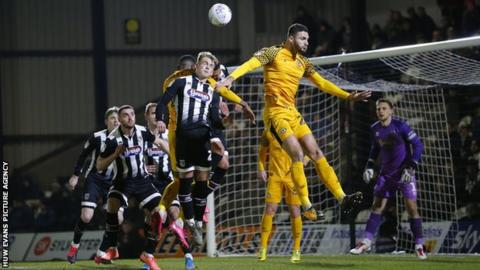 Ryan Inniss of Newport County rises to meet a corner