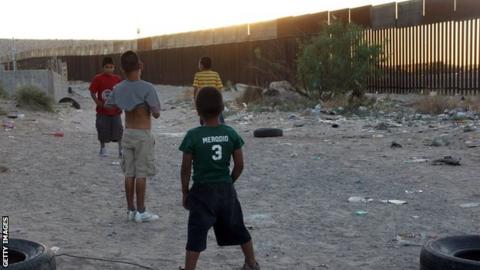Kids play football by US border in Ciudad Juarez