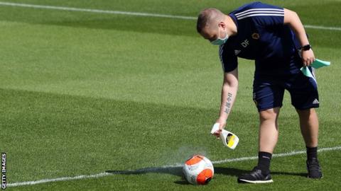 A member of staff sprays a ball with disinfectant