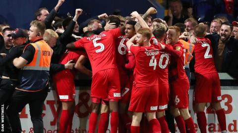 Leyton Orient players and interim head coach Ross Embleton celebrate their late winner with the travelling fans