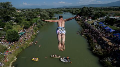 TOPSHOT - People look at a man as he jumps from the 22 meters high bridge 'Ura e Shenjte' during the annual traditional High Diving competition near the town of Gjakova on July 22, 2018. (Photo by Armend NIMANI / AFP) (Photo credit should read ARMEND NIMANI/AFP/Getty Images)