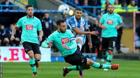 Richard Keogh tries to block a shot from Huddersfield's Nakhi Wells