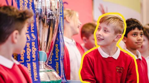 Young boys surrounding the Premier League trophy.