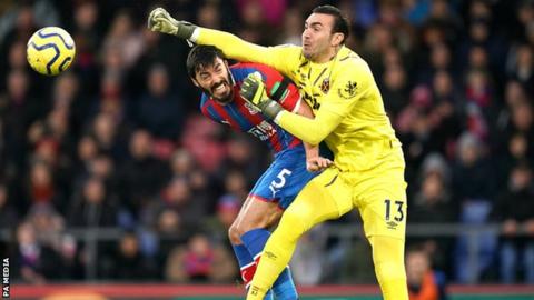 Roberto punches the ball away from a Crystal Palace player in a Premier League match