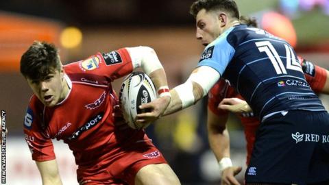 Steffan Evans of Scarlets beats tackle of Cory Allen and Alex Cuthbert