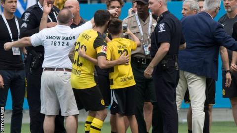 Christian Pulisic poses with a selfie with a young fan after stopping him from being dragged off the pitch by security guards