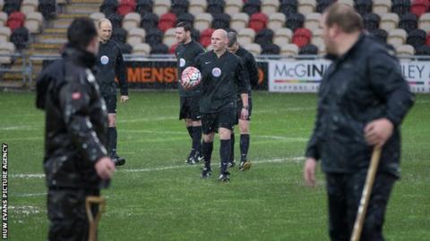 Referee Charles Breakspear inspects the Rodney Parade pitch as ground staff look on