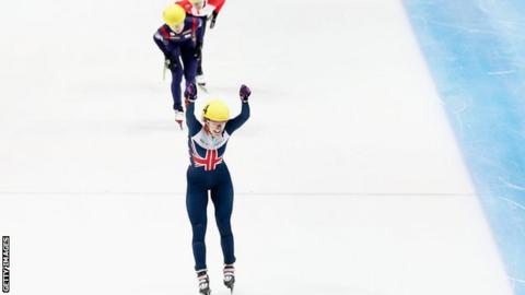 Elise Christie raises her arms aloft after winning the 1000m in Dordrecht