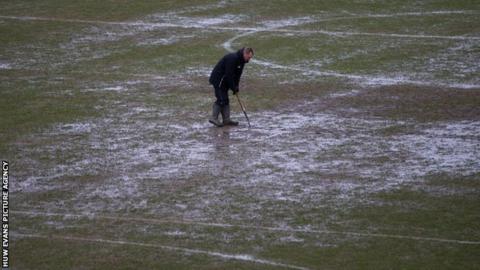 A groundsman battles with standing water on the Rodney Parade pitch in Newport