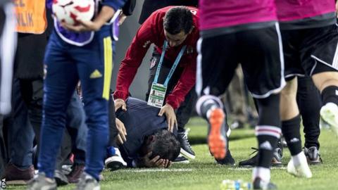 Besiktas boss Senol Gunes holds his head after being struck by an object from the crowd