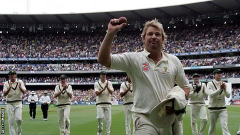 Australia leg-spinner Shane Warne holds up a ball to salute the crowd as he walks from the field after taking his 700th Test wicket in 2006