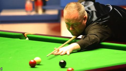 John Higgins plays a shot