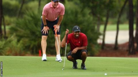 Tiger Woods and Peyton Manning line up a putt on the sixth green