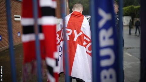 Bury fan stands at the gates of Gigg Lane