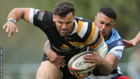 Arron Pinches of Merthyr is held by Duane Dyer of Bargoed