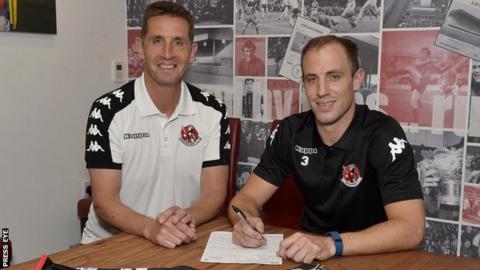 Crusaders boss Stephen Baxter watches on as Mark McChrystal signs for the Seaview club