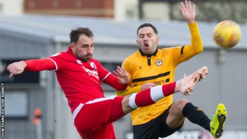 Josh Payne of Crawley Town clears under pressure from Robbie Willmott of Newport County