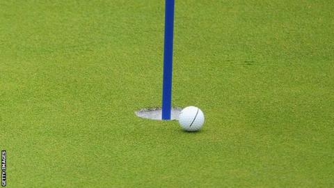 A golf ball going into the hole
