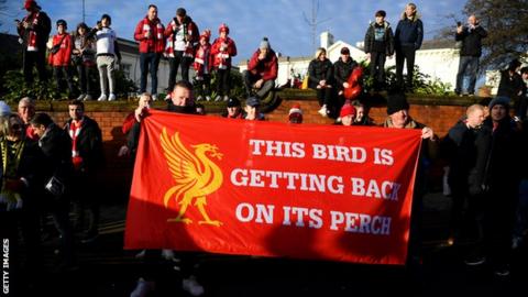 Liverpool fans with a flag saying 'The bird is getting back on its perch'
