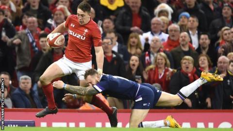 Josh Adams of Wales is tackled by Byron McGuigan of Scotland