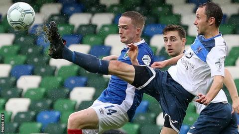 Ards midfielder David McCullough stretches to to beat Linfield's Aaron Burns to the ball