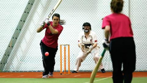 Women's playing cricket indoors