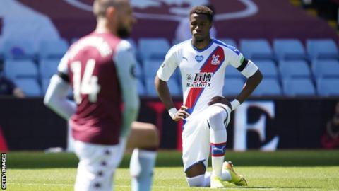 Wilfried Zaha kneeling before Crystal Palace's Premier League game at Aston Villa on Sunday