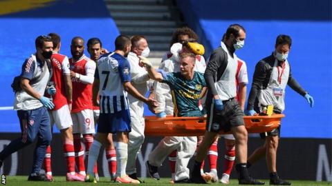 Bernd Leno points at Neal Maupay as he is carried off on a stretcher