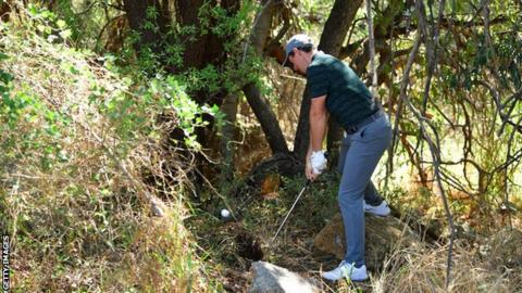 Rory McIlroy attempts an escape from the trees on the second hole on Saturday