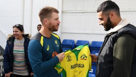 David Warner presents a signed shirt to Jaykishan Plaha, right, watched on by Plaha's mother, left