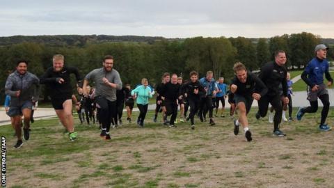 Runners running up grass-covered roof of Moesgaard Museum